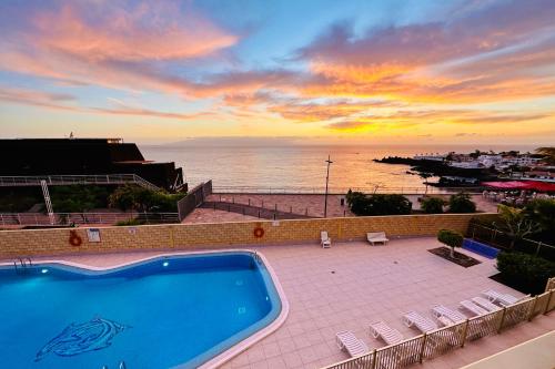 a swimming pool with a view of the ocean at sunset at Serigor Bahía Ocean View in Puerto de Santiago