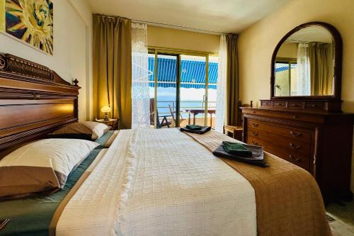 a bedroom with a large bed with a dresser and a mirror at Serigor Bahía Ocean View in Puerto de Santiago
