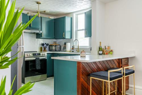 a kitchen with blue cabinets and a counter with stools at Jungle House Luxury Stays - Columbus Downtown Short North in Columbus