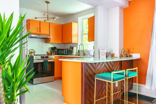 an orange kitchen with a counter and stools at Jungle House Columbus Short North Downtown Free Parking - Steps to Convention Center & Nationwide Arena - 2BR Luxury Home - Sleeps 8 - Over 5,800 Five Star Stays in Columbus