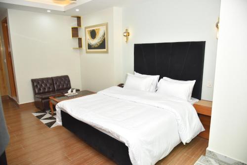 a bedroom with a large white bed and a chair at Modern Hotel with Free Wi-Fi Parking,210 in Muzaffarabad
