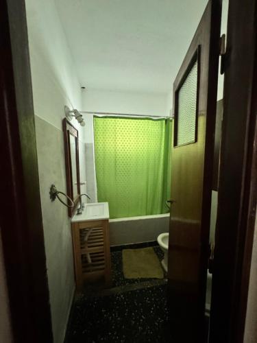 a bathroom with a green shower curtain and a toilet at casa en escobar con cocheras in Belén de Escobar
