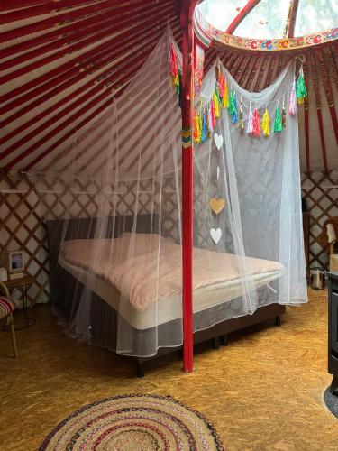 a bed in a yurt with a canopy at Het binnenerf yurt en keetjes in Nieuwleusen