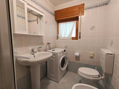 a bathroom with a washing machine and a sink at Appartamento panoramico 1 in Dosoledo