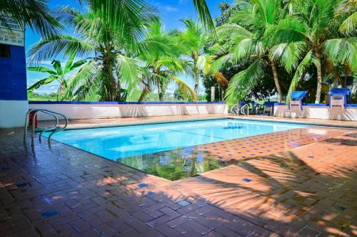 a swimming pool with palm trees in the background at El Ranchito de Turbo in Turbo