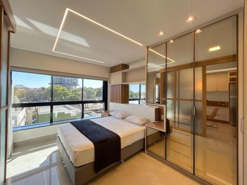 a bedroom with a large bed and a large window at Studio Central, Tranquilo e Confortavel in Campo Grande