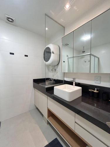 a white bathroom with a sink and a mirror at Studio Central, Tranquilo e Confortavel in Campo Grande