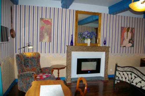 a living room with a fireplace and a chair and a mirror at Gîte Chez Jo in Longchamp-sur-Aujon