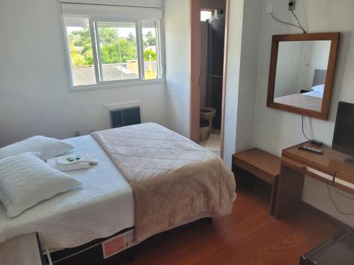 a bedroom with a bed and a mirror and a desk at Novo Hotel in Caçapava do Sul