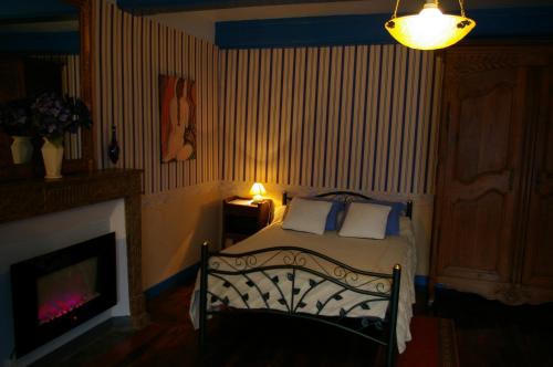a bedroom with a bed with a fireplace and a lamp at Gîte Chez Jo in Longchamp-sur-Aujon
