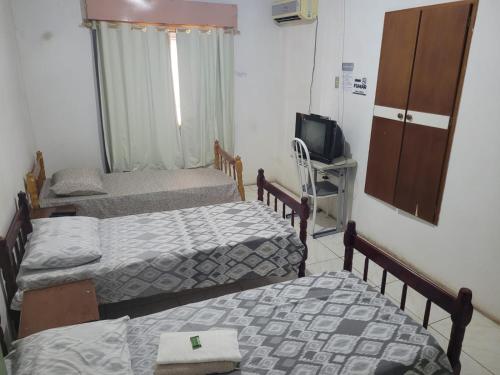 a room with three beds and a tv in it at Novo Hotel in Caçapava do Sul