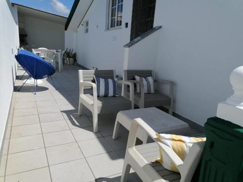 a patio with chairs and tables and a blue chair at Cantinho a Sul - Costa Nova in Gafanha da Encarnação