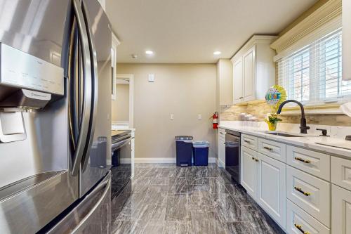a kitchen with white cabinets and a stainless steel refrigerator at Work, Play & Stay! Apt Near Holyoke Medical Center in Holyoke