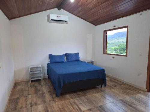 a bedroom with a blue bed and a window at Rancho Primavera in Santana do Riacho