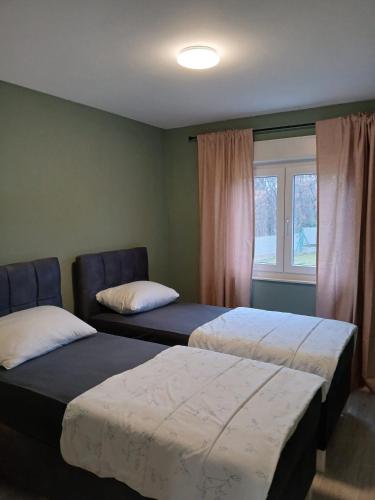 two beds sitting in a room with a window at Landhaus Olive in Čitluk