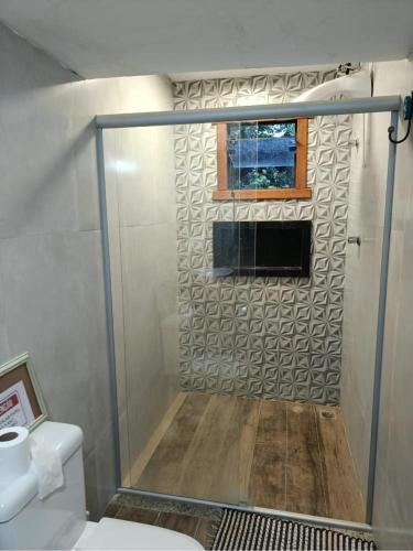 a bathroom with a shower with a window and a toilet at Rancho Primavera in Santana do Riacho