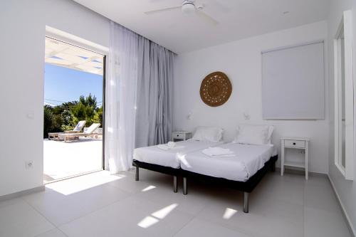 a white bedroom with a bed and a large window at serene villas in Ierapetra
