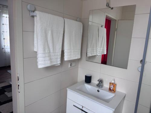 a bathroom with a sink and a mirror and towels at DanMa Ferienwohnung Apartment-Gemeinschaftsküche in Laubach
