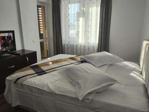 a bed with white sheets and pillows in a bedroom at Apartament Alice & Denis in Tohanu Nou