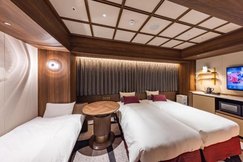 a room with two beds and a table and a tv at Hotel Keihan Asakusa in Tokyo