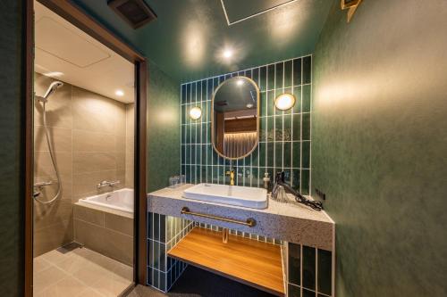 a bathroom with a sink and a mirror and a tub at Hotel Keihan Asakusa in Tokyo