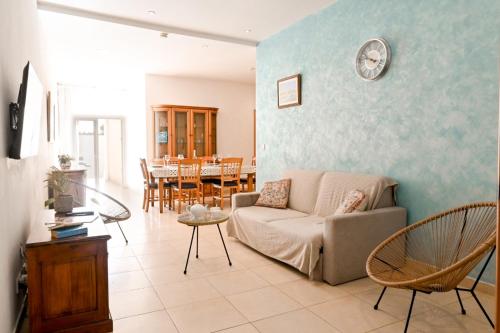a living room with a couch and a clock on the wall at Il-Qastna Holiday House in Żejtun
