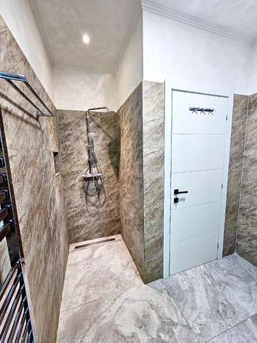a bathroom with a shower and a white door at Marconi Premium Apartments in Mamaia