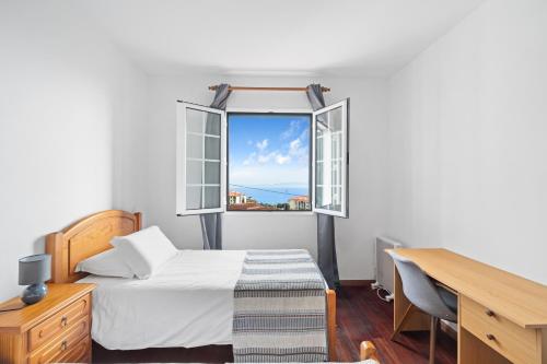 a bedroom with a bed and a desk and a window at Caniço Seaview House in Caniço
