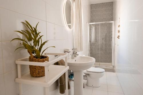 a white bathroom with a toilet and a sink at Il-Qastna Holiday House in Żejtun
