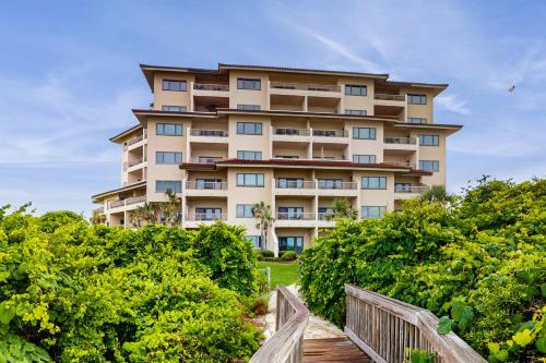 a large apartment building with a wooden walkway in front at Ocean Front Hotel Side Condo with Balcony, WiFi & Shared Pool in Fernandina Beach