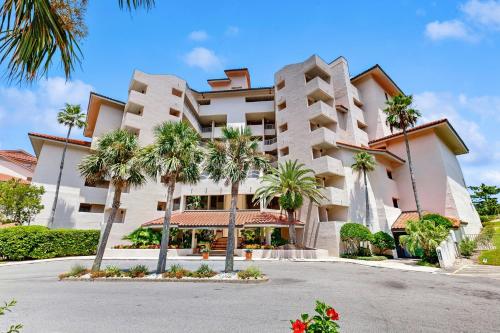 a building with palm trees in front of it at Ocean Front Hotel Side Condo with Balcony, WiFi & Shared Pool in Fernandina Beach
