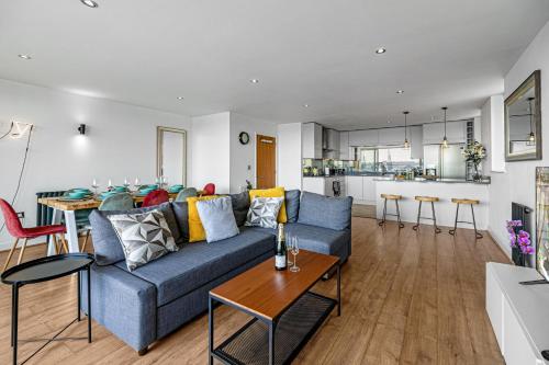a living room with a blue couch and a table at Spacious Excel London Apartment with Balcony, River View and Parking Sleeps 8 in London