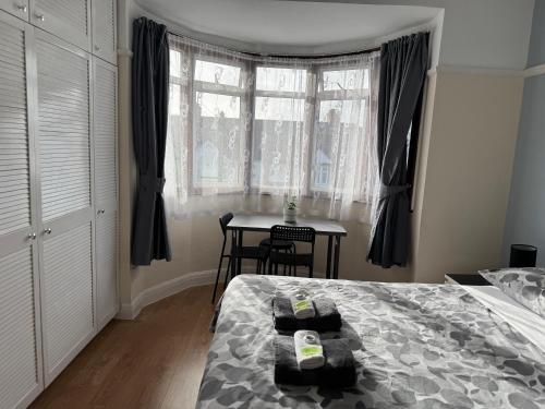 a bedroom with a bed and a table and a window at North West Lodge Guest House in London