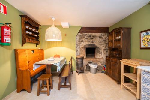 a kitchen with a table and a stone fireplace at Aldea A Paínza in Arzúa