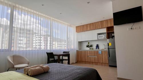 a bedroom with a bed and a kitchen with a table at Nuevo y moderno departamento Quito Norte in Quito