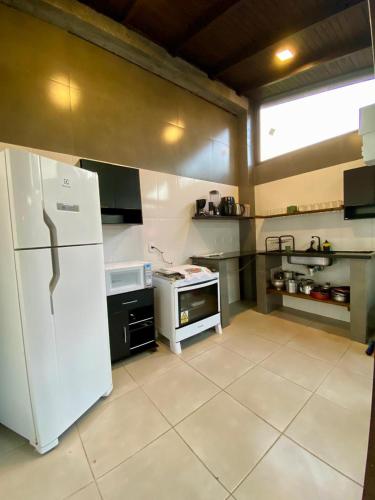 a kitchen with a white refrigerator and a stove at Hospedaria aconchego master in Garopaba