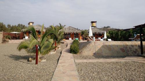 a resort with palm trees in front of a building at Guille Bungalows in Canoas De Punta Sal