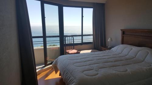 a bedroom with a large bed and a view of the ocean at Fortezuelo - Atardecer in Viña del Mar