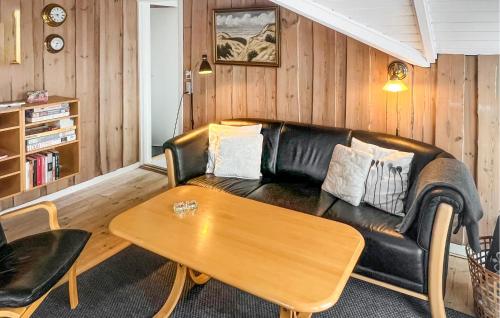 a living room with a leather couch and a table at Holiday Home Hvide Sande 20 in Bjerregård