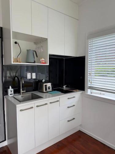 a kitchen with white cabinets and a sink and a window at Irina's bnb in Auckland