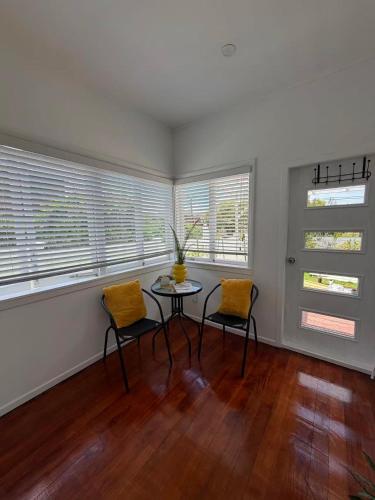 a room with a table and two chairs and windows at Irina's bnb in Auckland