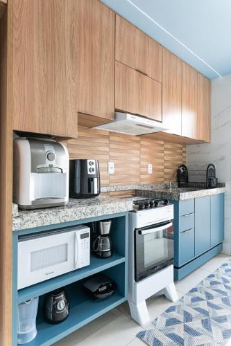 a kitchen with wooden cabinets and a blue counter top at Flat Coqueiros 101 Praia in Tamandaré