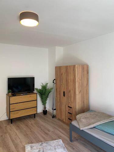 a bedroom with a bed and a tv and a wooden cabinet at moderne Ferienwohnung Nähe Goitzschesee in Greppin