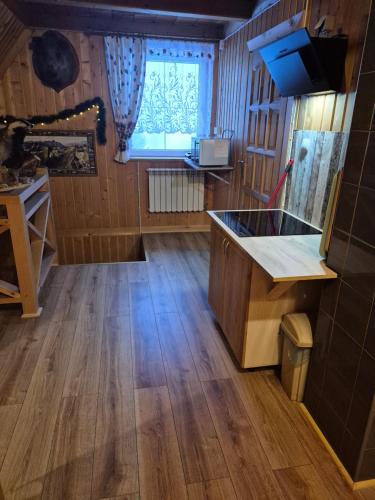 a kitchen with wooden floors and a large window at Miodowa Chatka in Brzegi