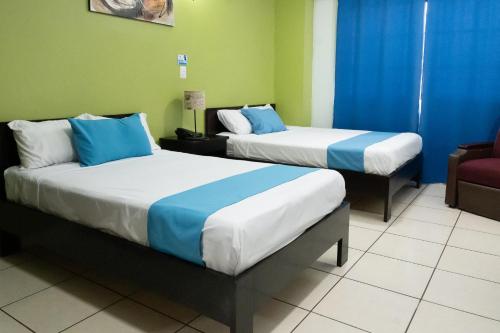 two beds in a room with blue and green at Hostal de Asturias in San Salvador