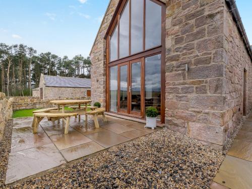 a stone house with a picnic table in the courtyard at Haybale Barn in Chatton