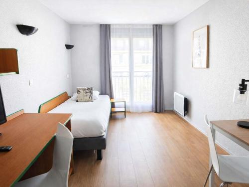 a hotel room with a bed and a table and a desk at Aparthotel Adagio Access Paris Maisons-Alfort in Maisons-Alfort