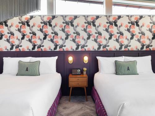 two beds in a room with a wall with flowers at ARRIVE Palm Springs - Adults Only in Palm Springs