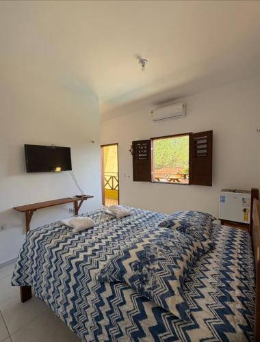 a bedroom with a bed and a flat screen tv at Pousada Águas Claras in Jijoca de Jericoacoara