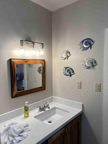 a bathroom with a sink and a mirror and fish decals at The Flying Toucan Beach Rentals in Placencia